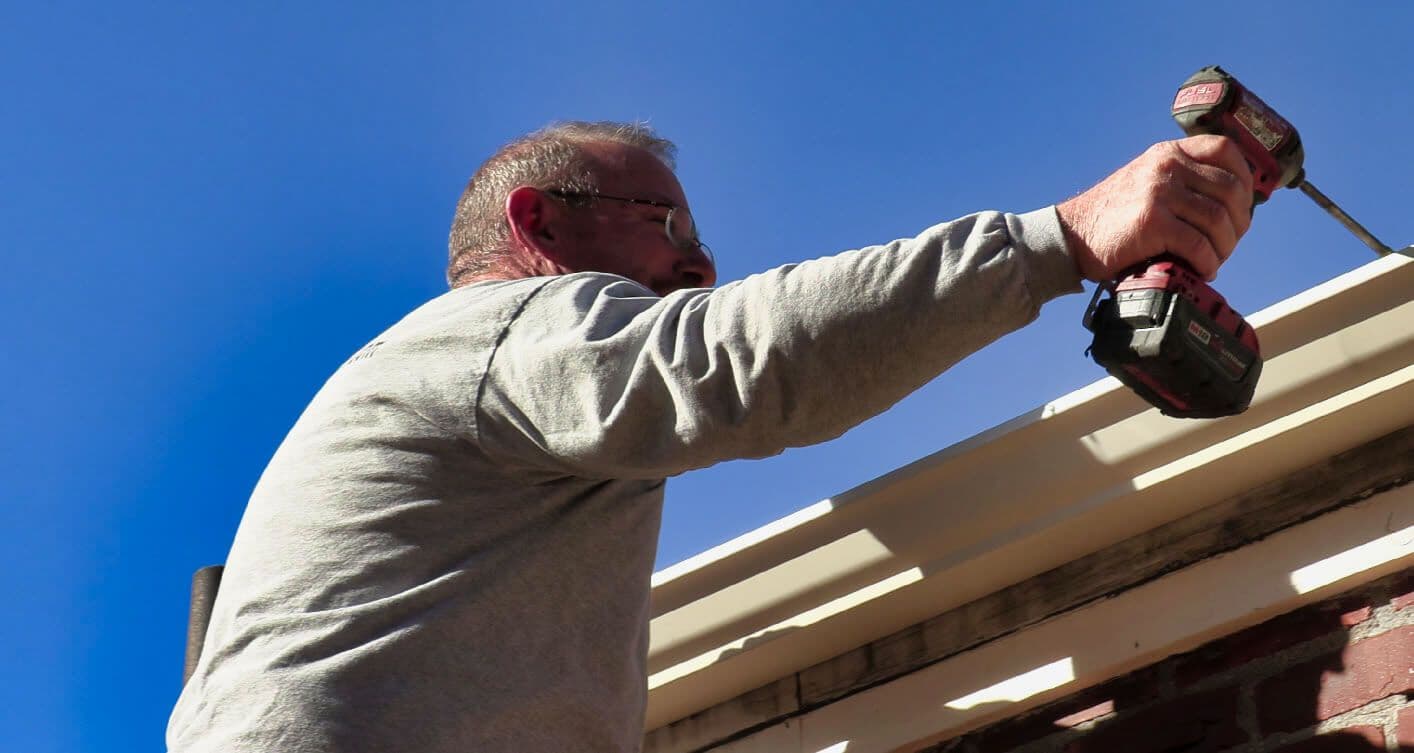 A&A technician using cordless drill to secure gutters